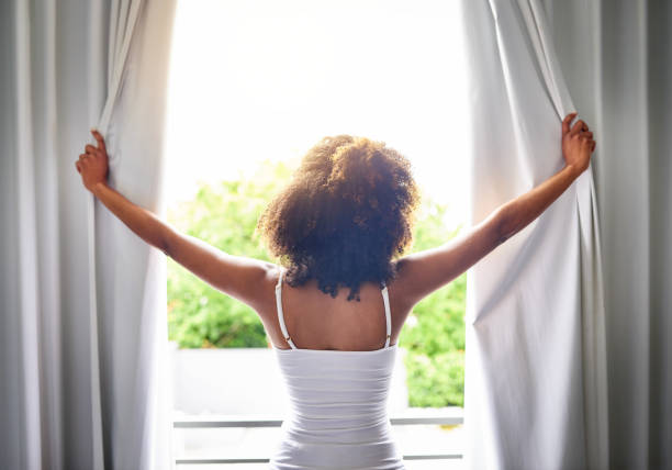 a women sliding the curtains in the morining and straring a day with a ayurvedic morining ritual