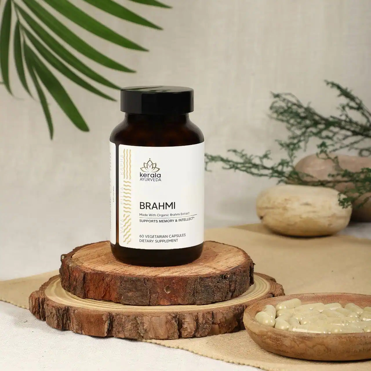 A bottle of Kerala Ayurveda Brahmi, containing 60 vegetarian capsules, marketed as supporting memory and intellect, placed on a wooden coaster with beige background