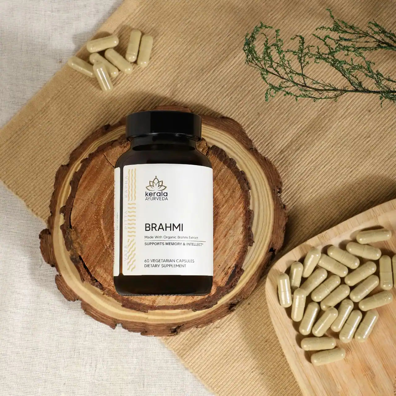 A bottle of Kerala Ayurveda Brahmi, containing 60 vegetarian capsules, lying on a wooden coaster with capsules around the bottle