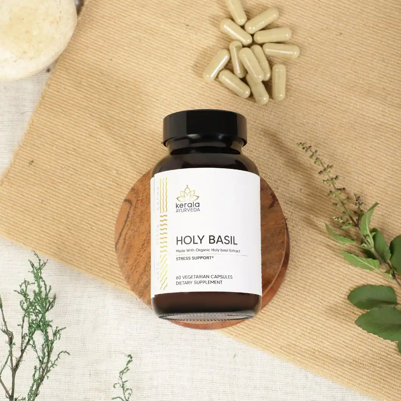 A bottle of Kerala Ayurveda Holy Basil dietary supplement with 60 vegetarian capsules, labeled as stress support with capsule lying around the bottle