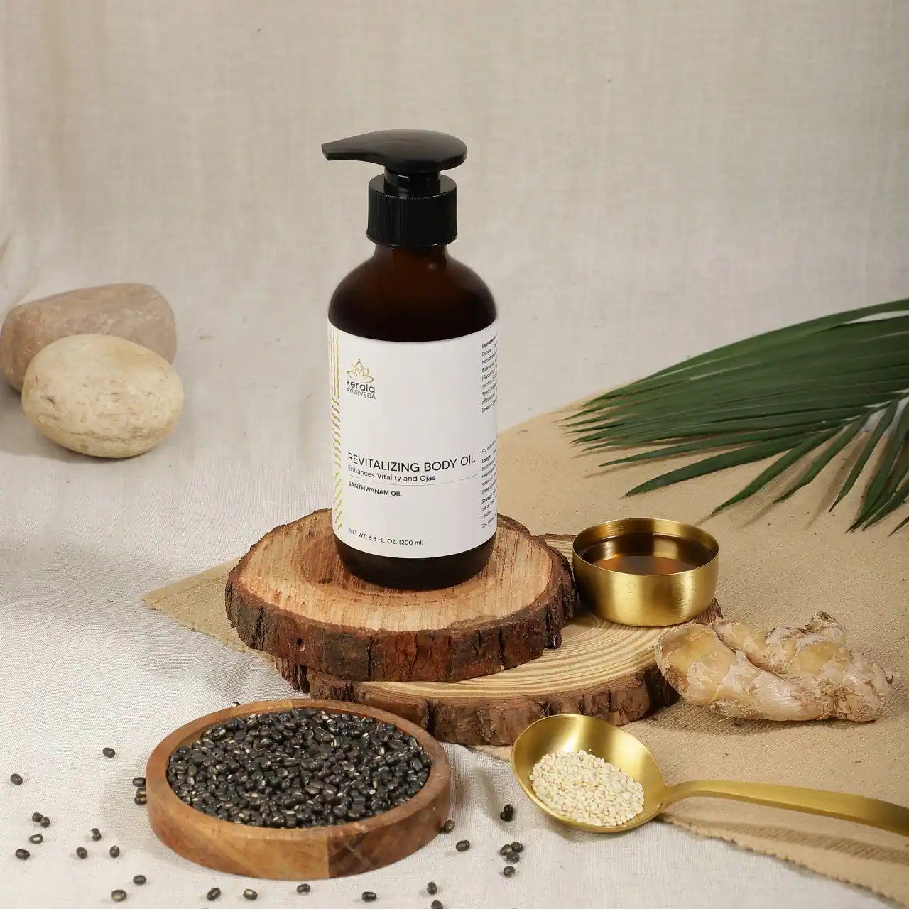 A bottle of Revitalizing Body Oil with a label that includes the brand name Kerala and the product name. The oil is in a clear amber bottle with a black pump with a beige background and spices lying around