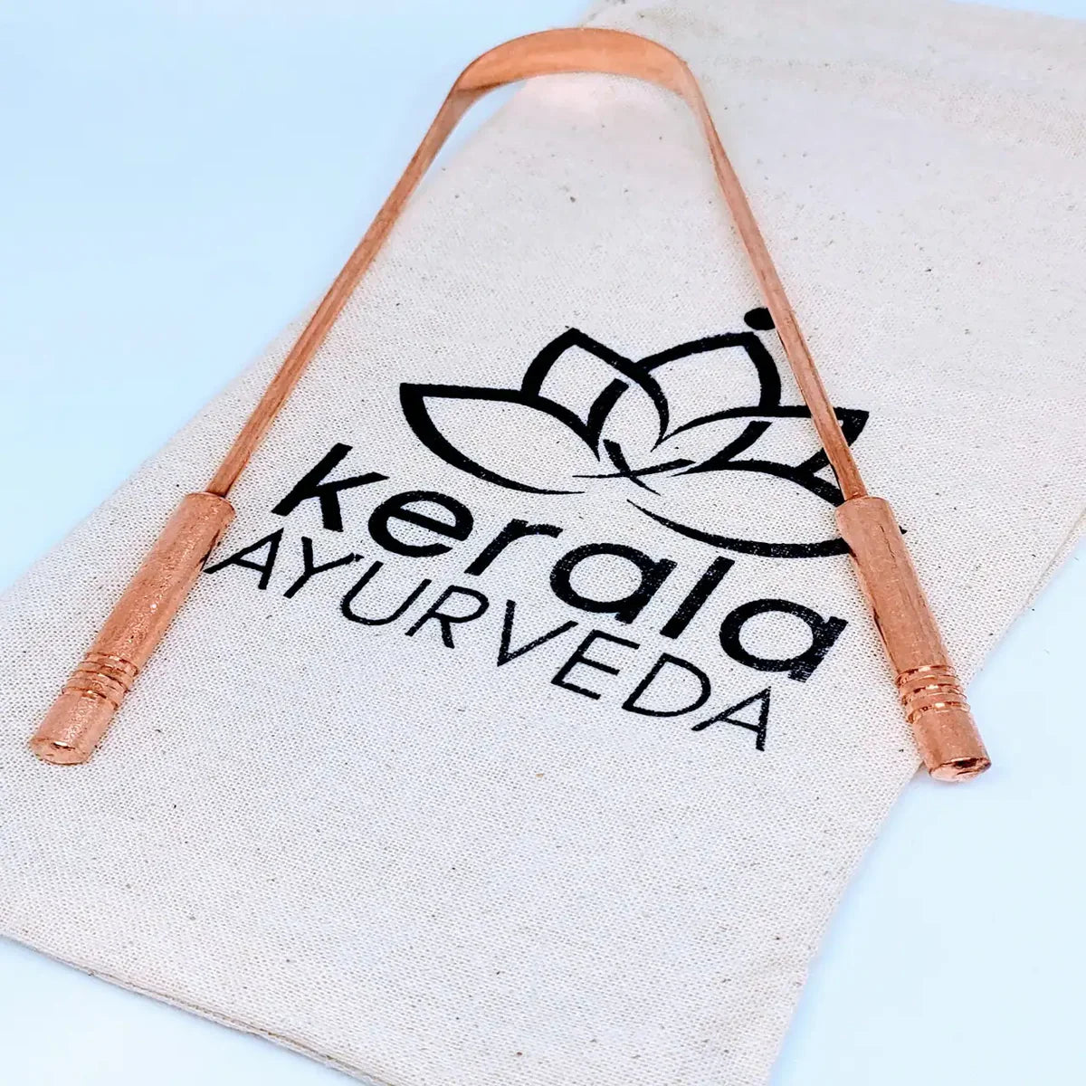 Canvas pouch with 'Kerala Ayurveda ' logo and copper handles on a light blue background.